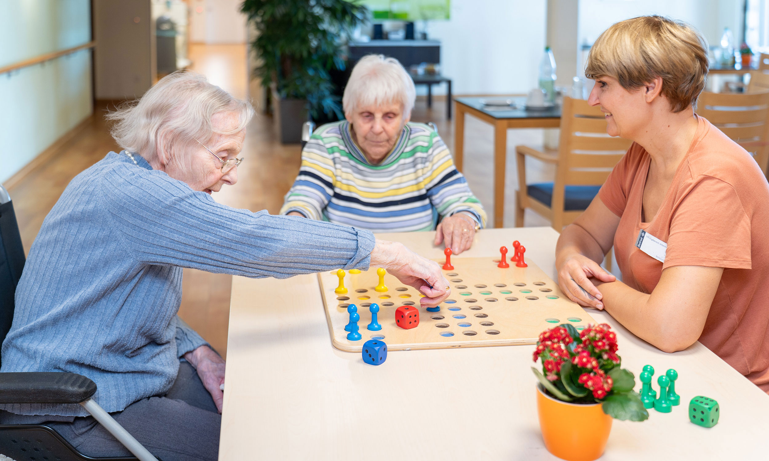 Zwei Bewohnerinnen spielen mit einer Betreuerin ein Brettspiel